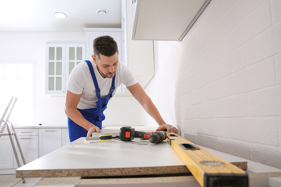 Worker installing new countertop in modern kitchen